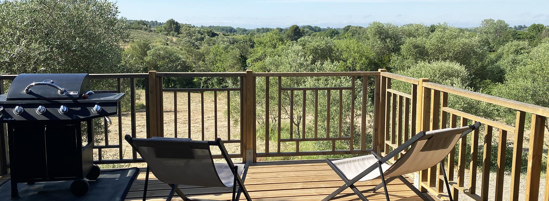 Terras van een stacaravan met ligstoelen, te huur op camping Les Amandiers in Hérault