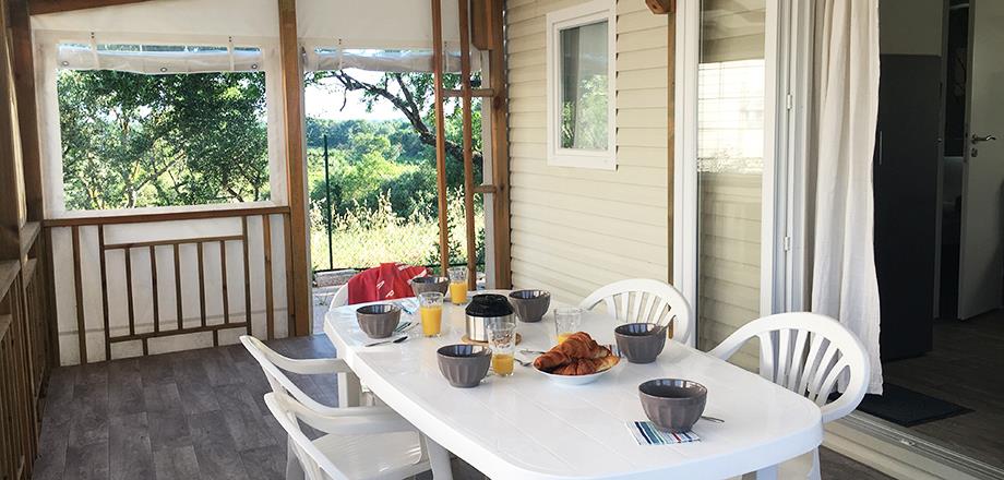 Overdekt terras met tuinmeubilair en ligstoelen in de 3-slaapkamer stacaravan Cottage; te huur op camping les Amandiers in Castelnau de Guers