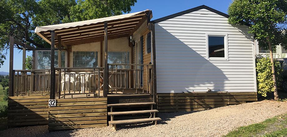 Vue extérieure du mobil-home Cottage et sa terrasse couverte, en location au camping les Amandiers dans l’Hérault