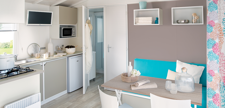 La cocina y el comedor del mobil home Loggia para 4 personas, en alquiler en el camping Les Amandiers de Castelnau de Guers.