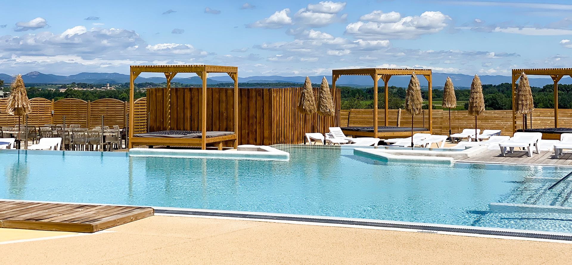 The aquatic area with swimming pool and deckchairs of the campsite Les Amandiers near Pézenas in Castelnau de Guers