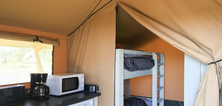 Coin cuisine équipé et la chambre avec 1 lit superposé de la tente Safari toilée, en location hébergement insolite au camping les Amandiers